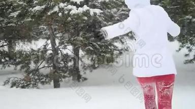 迷人的年轻女子在雪地里奔跑，在雪地里摇动着雪枝，在雪地里缓慢的运动中享受冬天